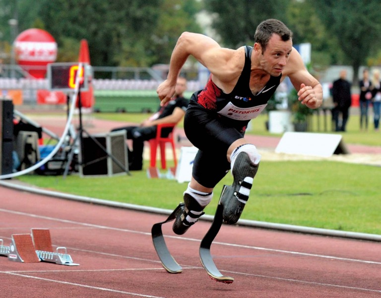Định mệnh đã lấy đi của Oscar Pistorius đôi chân, khiến anh phải sống đời tàn tật từ khi cất tiếng khóc lọt lòng. Nhưng từ sâu thẳm trái tim mình, “người không chân” chưa bao giờ có ý nghĩ đầu hàng số phận. Hơn mười năm miệt mài băng mình trên đường chạy, nâng cơ thể mình bằng đôi chân sợi các-bon, Pistorius muốn chứng minh cho cả thế giới thấy rằng những người không may bị khuyết một phần cơ thể như anh vẫn có quyền mơ đến mọi đỉnh cao. Olympic 2012, Pistorius cuối cùng đã thỏa nguyện. Oscar Pistorius – “Người không chân” chinh phục cả thế giới Qua cơn đau bằng máu và nước mắt Pistorius đã trở nên nổi tiếng khắp thế giới, kể từ khi anh bước ra đấu trường Paralympic 2004 và giành mọi HCV ở những cự ly chạy quan trọng nhất. Tại Athens năm đó, hàng vạn khán giả đã tung hô anh như một thần tượng lớn với danh hiệu người không chân chạy nhanh nhất hành tinh. Nhưng ở Nam Phi, thay vì cái danh hiệu dài lê thê đó, người ta vẫn trìu mến gọi anh bằng cái tên Oscar. Một đồng đội bình thường (hoàn toàn lành lặn) ở đội tuyển điền kinh Nam Phi dự Olympic 2012 đã lý giải: “Chỉ với cách gọi ấy, chúng tôi mới thể hiện được hết lòng kính phục của mình. Oscar không chỉ là một VĐV thể thao xuất sắc. Nỗi bất hạnh cuộc đời mà anh ấy phải chịu đựng và vượt qua xứng đáng là một biểu tượng về ý chí vươn lên cho hàng tỷ người trên khắp hành tinh này”. Người đồng đội của Pistorius không hề quá lời. Tại đất nước từng sản sinh ra huyền thoại Nelson Mandela, từng giành quyền đăng cai vòng chung kết World Cup 2010, Oscar Pistorius vẫn thường được mang ra làm tấm gương cho lũ trẻ. Khi các nhà báo nước ngoài lặn lội về tận Nam Phi trước Thế vận hội 2012, họ đã được nghe kể về quá khứ đầy nước mắt của Oscar. 11 tháng tuổi, anh đã bị bác sỹ kết luận căn bệnh không có xương mác bẩm sinh là vô phương chữa trị. Vì căn bệnh ấy, Oscar không thể có chân và suốt cuộc đời phải gắn bó cùng đôi chân giả hoặc chiếc xe lăn. Tuổi ấu thơ trải qua nhiều ký ức về một nỗi ám ảnh kinh khủng. Pistorius từng kể rằng anh đã khóc hàng trăm lần khi nhìn những đứa trẻ cùng trang lứa với mình đá bóng, chạy chơi trên đường hoặc làm bất cứ điều gì đó với đôi chân lành lặn, nhưng nỗi đau lớn ấy không thể đánh gục ý chí của Pistorius. Thay vì tự thu mình vào bóng tối, Pistorius xin cha mẹ đưa đến bệnh viện để tìm kiếm cơ hội khôi phục” đôi chân. Chuyện tái tạo xương mác dĩ nhiên là vô vọng, song các bác sỹ đã giúp Pistorius một đôi chân sợi các-bon rất bền và vừa vặn để anh tập chạy hàng ngày. Tâm sự cùng báo giới bên lề Olympic, “người không chân” bảo rằng suốt hơn mười năm qua, anh đã chạy nhiều đến mức điểm tiếp xúc giữa cơ đùi với đôi chân sợi các bon tứa máu đầy đau đớn. Có những lúc, sự mệt mỏi quá độ về thể xác thậm chí khiến anh phải ngã gục ngay trên đường chạy của mình, nhưng Oscar Pistorius đã vượt qua tất cả bằng thần kinh thép và nghị lực phi thường. Câu chuyện về một huyền thoại Olympic bắt đầu, chính từ những tháng ngày cay cực như thế. “Bay” trên đỉnh cao Lẽ ra, Oscar Pistorius đã có thể tham dự Olympic từ năm 2008. Thời điểm đó, một nghiên cứu của Trường đại học Cologne (Đức) nói rằng Pistorius sẽ tiêu tốn ít hơn các vận động viên bình thường khác 25% năng lượng nhờ đôi chân sợi các-bon nên không thể để anh thi đấu tại vòng loại Olympic. Vì chuyện này, Oscar Pistorius đã quyết định khiếu nại. Dù Liên đoàn điền kinh thế giới sau đó đã xử thắng cho Pistorius, nhưng việc mất quá nhiều thời gian vào vụ lùm xùm này đã khiến anh không đạt được thành tích đủ tốt để giành vé chính thức đến Bắc Kinh. 4 năm sau, câu chuyện đã hoàn toàn khác. Việc Liên đoàn điền kinh thế giới chính thức cho phép Pistorius thi đấu tại giải Vô địch thế giới tổ chức năm 2011, giống như một sự thừa nhận mặc nhiên rằng Oscar Pistorius phải được đối xử như bất kỳ vận động viên bình thường nào. Phấn khích, Oscar Pistorius đã vượt qua thành tích chuẩn A để đường hoàng giành vé dự Thế vận hội London 2012. Từ đây, một chương mới của thể thao thế giới đã mở ra khi Oscar trở thành vận động viên khuyết tật đầu tiên trong lịch sử dự một kỳ Olympic. Cả đất nước Nam Phi ăn mừng sự kiện đó một cách tự hào. Oscar đã trở thành biểu tượng cho nghị lực, lòng quả cả của cả một dân tộc và Tổng thống Mbeki, thậm chí đã đề nghị Oscar Pistorius nên cầm cờ cho Đoàn thể thao Nam Phi trong lễ khai mạc. Thời khắc lịch sử đã đến hôm 4/8. Oscar Pistorius xuất hiện trên sân Olympics trong sự hò reo của 8 vạn người. Anh khởi động, bước lên bục xuất phát và bứt lên kết thúc vòng loại với vị trí thứ 2 chung cuộc. “Người không chân” đã “chạy” vào đến vòng bán kết cự ly chạy 400m bên cạnh những kỷ lục gia lành lặn. Dù không thể giành được một tấm huy chương sau đó, Pistorius đã khoác lên mình lá cờ Nam Phi. Anh ăn mừng tấm huy chương của riêng mình, tấm huy chương có ý nghĩa không kém gì những kỷ lục thế giới hay Olympic đã được thiết lập bởi những siêu sao lừng danh khác. Từ hôm nay, cả thế giới sẽ phải nghiêng mình chào đón một huyền thoại: Oscar Pistorius Siêu nhân tại Paralympic 2012? Cũng giống như Usain Bolt, Oscar Pistorius đã thống trị toàn bộ những cự ly chạy quan trọng nhất tại Paralympic 4 năm về trước. Trên đất Bắc Kinh, Oscar đã giành 3 HCV trên đường chạy 100m nam, 200m nam và 400m nam. London 2012, ở tuổi 25 sung sức nhất và sau màn trình diễn cực kỳ ấn tượng tại Olympic, Oscar Pistorius được dự báo sẽ bảo vệ dễ dàng những đỉnh cao vinh quang của mình. Một quan chức của Liên đoàn điền kinh thế giới đã ví von: “Nếu coi Usain Bolt là một siêu nhân tại Thế vận hội, thì Oscar chính là siêu nhân ở đấu trường Paralympic”